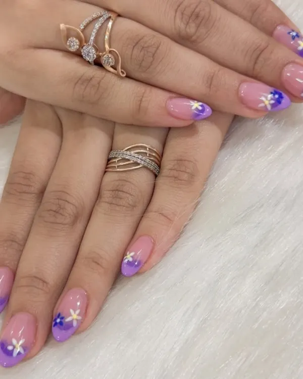A beautiful example of a soft color transition. These nails feature a purple ombré fade, complemented by small, hand-painted flowers.