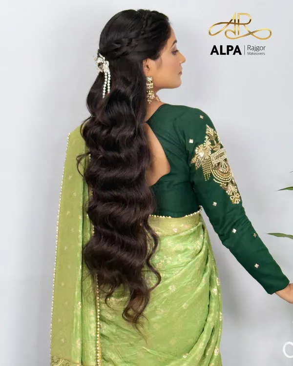 A beautiful half-up, half-down hairstyle for very long hair, featuring soft waves and a delicate braid. This look is perfect for a reception or Sangeet.