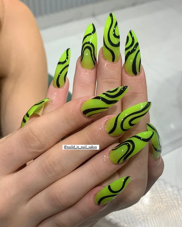 The ultimate bold look. Extra-long stiletto nails in a shocking neon green are covered in hand-painted black abstract swirls for a high-impact, graphic effect.