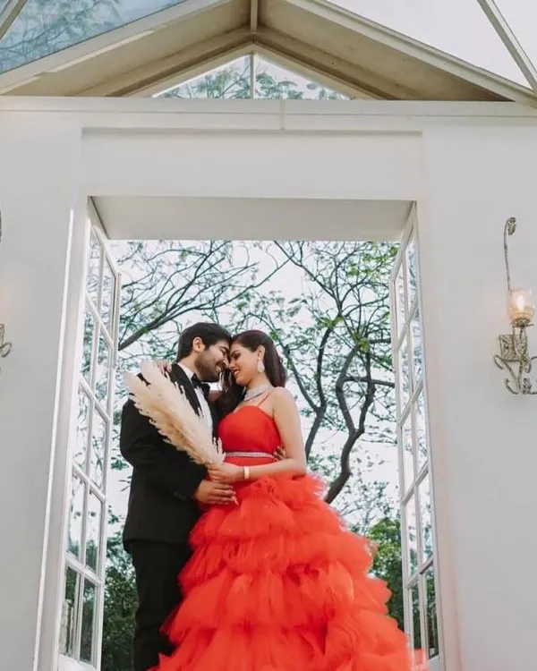 A romantic close-up of a couple, with the bride-to-be in a stunning red ruffled gown. This dress is a favorite for pre-wedding photoshoots because of its vibrant color and texture.