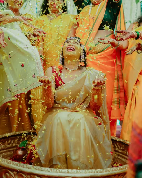 A moment of pure bliss as the bride is showered with flower petals during her Haldi ceremony. Her joyful laughter is infectious.