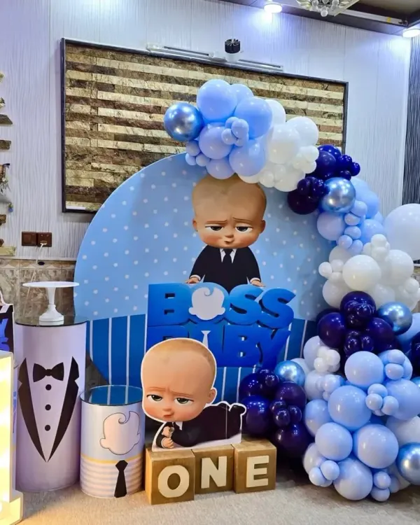 A complete Boss Baby theme for a first birthday, featuring multiple character cutouts, a custom backdrop, "ONE" blocks, and a light-up marquee number.