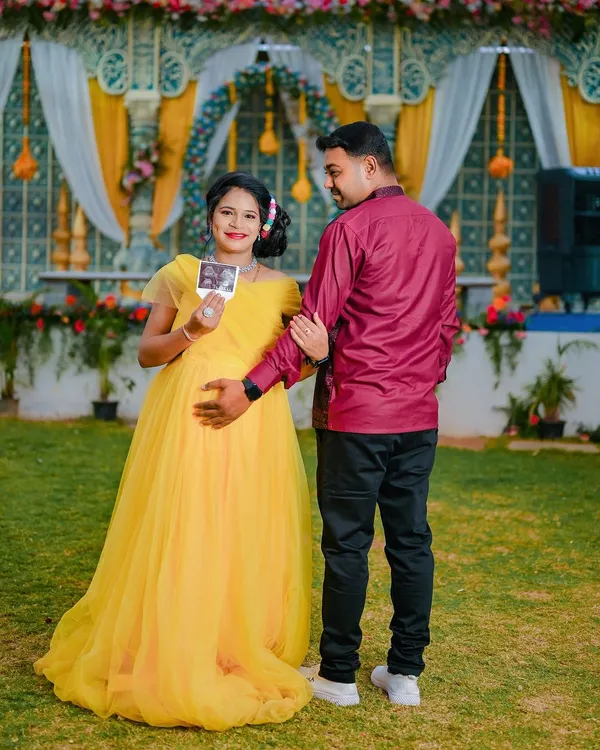 An outdoor maternity shoot celebrating the upcoming arrival. This couple wanted to announce their joy with cute props like baby shoes and their ultrasound picture, set against a beautiful event backdrop.