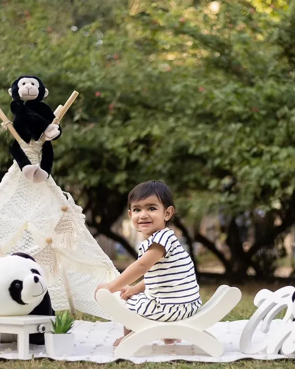 An outdoor first birthday shoot with a cute panda and teepee theme. The natural greenery provides a beautiful backdrop.