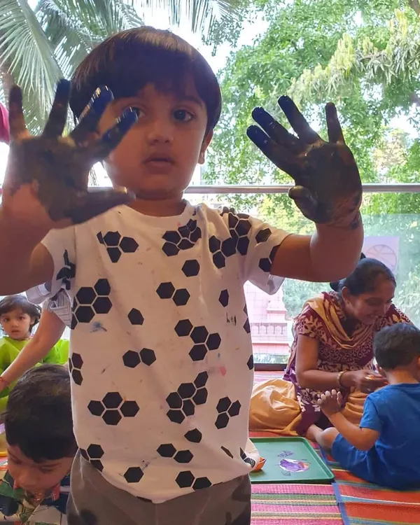 Messy hands, happy heart! This is the sign of a successful art class. This little boy is showing off his paint-covered hands after a fun session of sand and process art.
