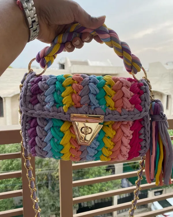 This is my crochet "marshmallow" bag in a vibrant rainbow design. It's made from soft T-shirt yarn and is surprisingly lightweight, with a chunky gold chain that makes it a real statement piece.