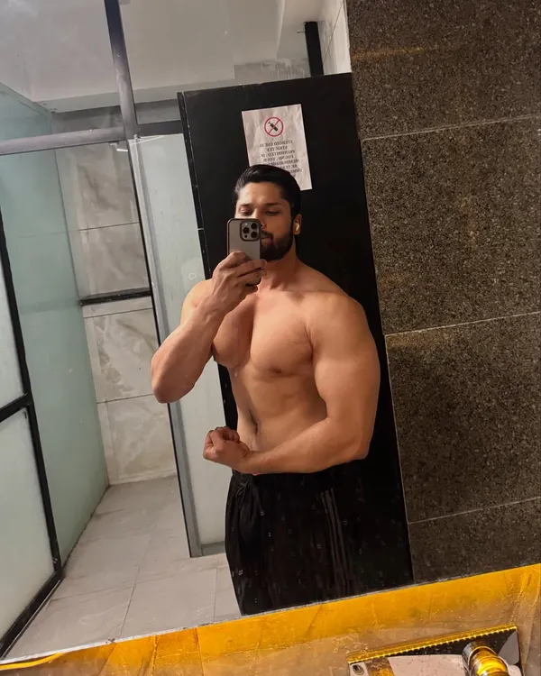 A shirtless mirror selfie showing chest and arm development. This is what being an absolute unit looks like.