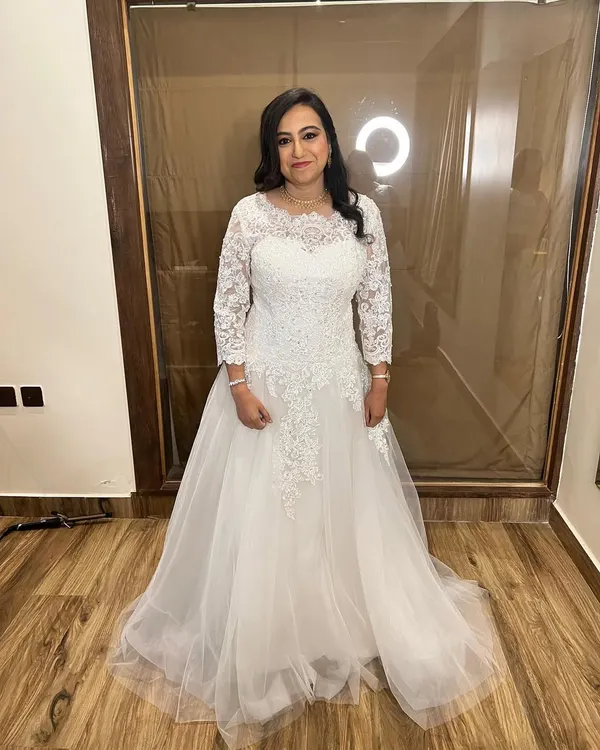 The quintessential Christian bride. This full-length view shows the bride in her beautiful lace and tulle gown. Her makeup is soft and natural, and her hair is styled elegantly to complete the look.