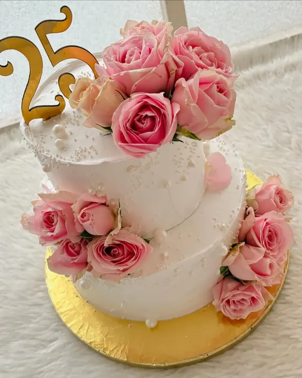 A stunning two-tier cake for a 25th anniversary, decorated with dozens of fresh pink roses. The design is classic, romantic, and perfect for such a special milestone.