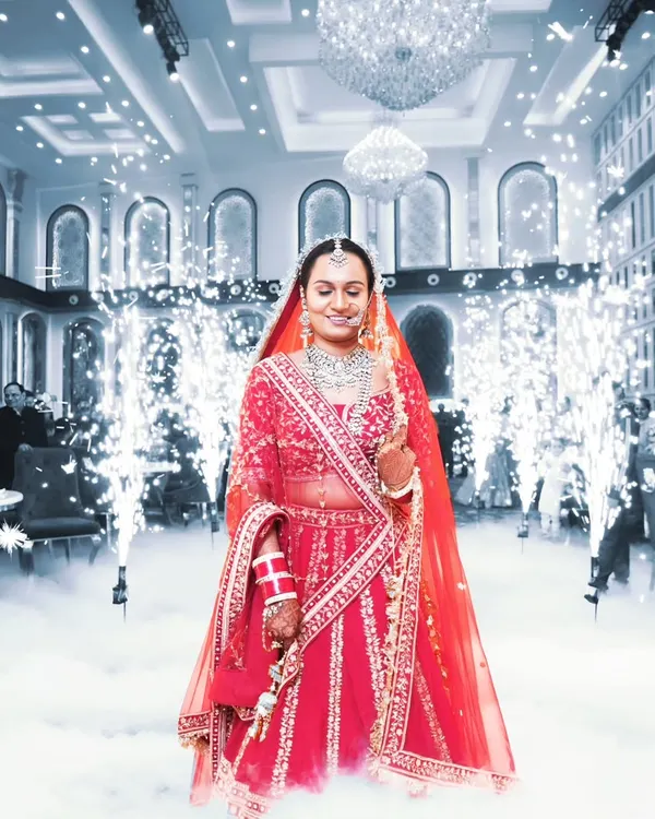 We create unforgettable bridal entry moments. Here, the bride makes her grand entrance through a path of cold pyrotechnics and low-lying fog, creating a truly magical atmosphere for her wedding reception in a Noida banquet hall.