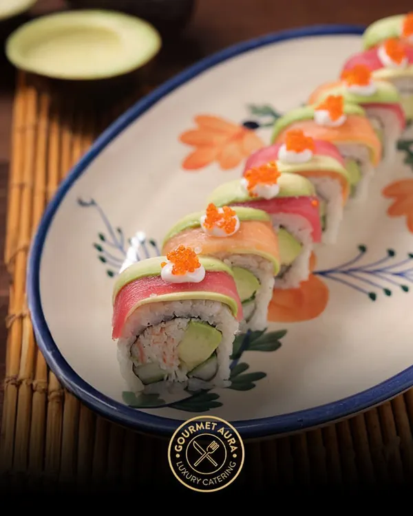 A vibrant rainbow roll, showcasing layers of fresh tuna, salmon, and avocado, topped with bright orange tobiko. This is a perfect example of our commitment to both flavor and visual artistry in our sushi offerings.