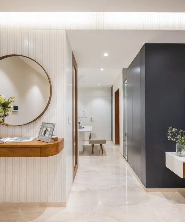 The foyer sets the tone for this minimalist home. A floating wood console against a white fluted wall and a dark accent wall for the TV unit create a striking contrast and a clear path into the living area.