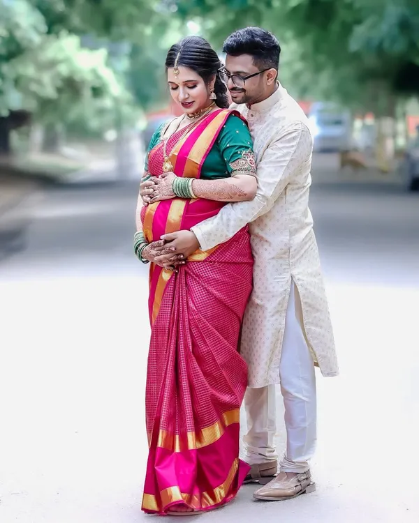 A classic pose celebrating the journey to parenthood, set against the backdrop of a traditional baby shower ceremony. The embrace signifies support and shared excitement.