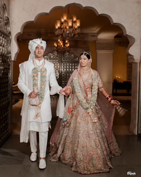 A royal union deserves a regal setting. Here, the couple walks hand in hand through the magnificent archways of a Jaipur palace, their traditional attire complementing the grandeur of their surroundings. This is a portrait of heritage and love intertwined.