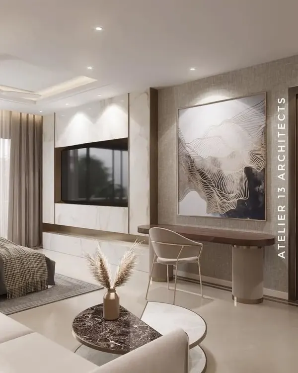 This master bedroom combines a cozy bed with a functional workspace. The TV unit is crafted from white marble with brass inlay, and a large abstract artwork adds a touch of modern sophistication to the serene space.