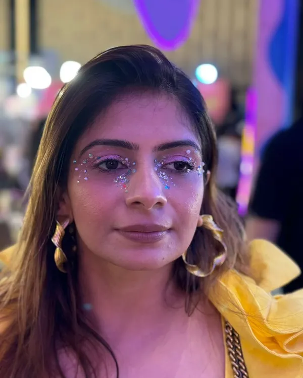 A client looking radiant with a custom silver glitter and gem design under her eyes, perfect for the Coachella party vibe.