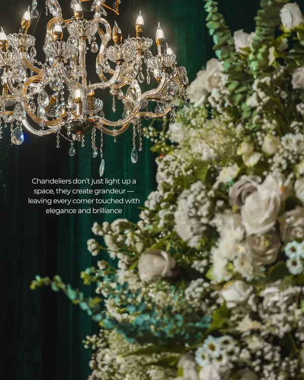 A classic crystal chandelier paired with lush white florals against a deep green velvet backdrop. This combination creates a sense of timeless grandeur and sophistication, ideal for a luxury event or gala.