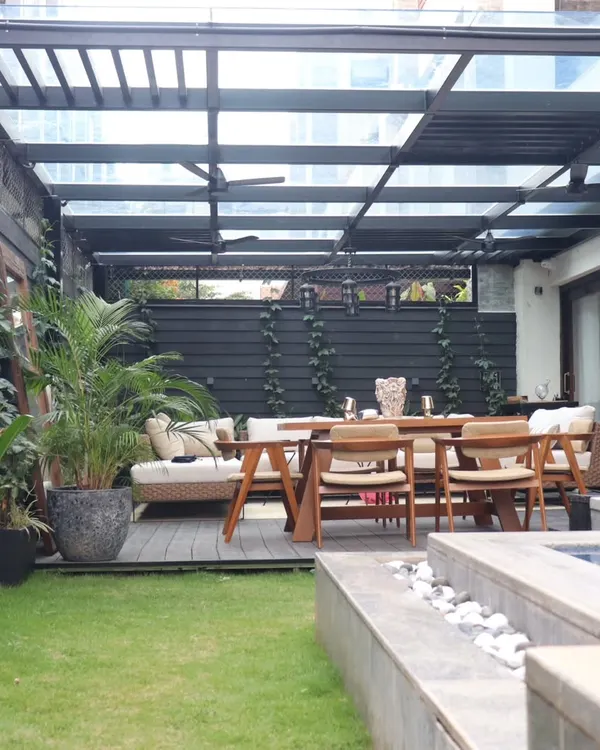 We designed this elegant backyard retreat featuring a sleek glass pergola that provides shelter without sacrificing light. The space combines a durable composite deck for dining, a lush natural lawn, and carefully selected plants to create a perfect balance of structure and nature.