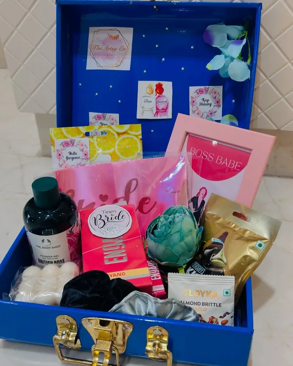 Inside a beautiful bridal hamper trunk. This gift is packed with essentials like The Body Shop products, a 'Boss Babe' frame, sweet treats, and a 'Team Bride' sash for the bride-to-be.