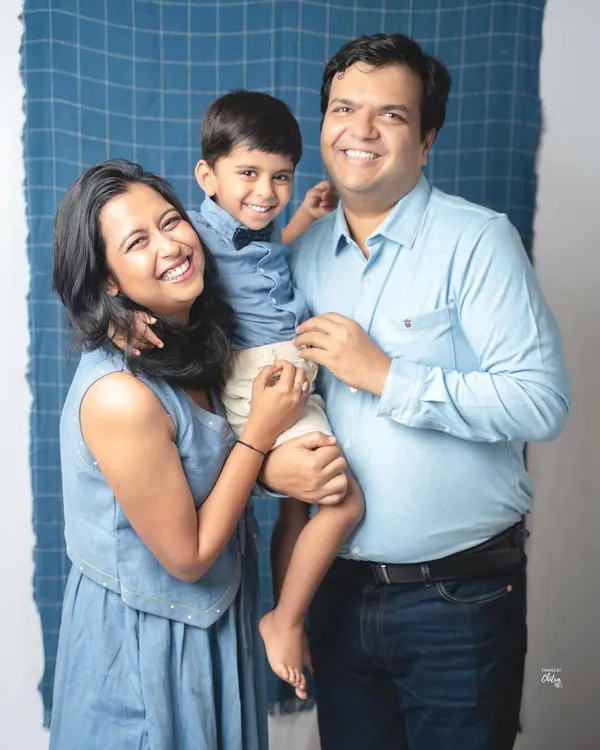 A perfect family hug. The coordinated denim and blue outfits look wonderful against the simple backdrop, and their bright, happy smiles are absolutely infectious.