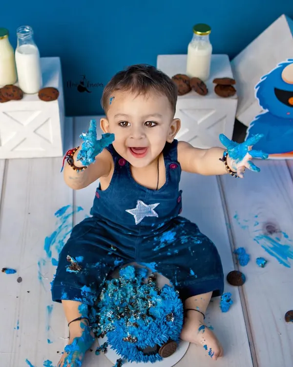 The pure joy of a cake smash! This little Cookie Monster is having the best time, with blue frosting on his hands and a huge smile on his face.