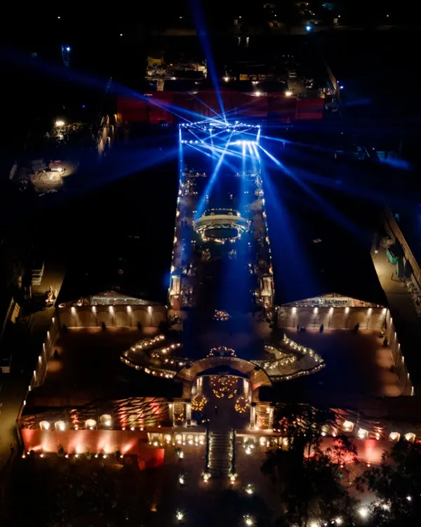 An incredible aerial view of the 'Lost City' project at night. This shot reveals the immense scale of the 100,000 sq. ft. venue, with the grand stage illuminated by a dramatic light show, creating a truly otherworldly spectacle.