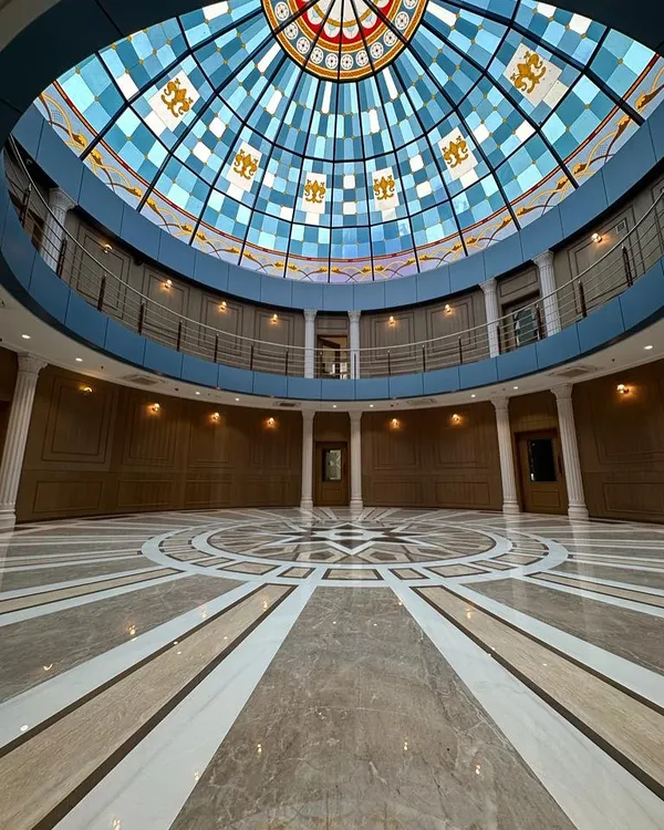 The completed grand lobby of the Arihant Aspire clubhouse, featuring Mumbai's largest glass dome. The intricate marble flooring and wood-paneled walls create a sense of timeless elegance and scale.