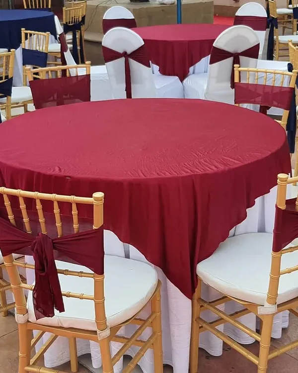 We provide elegant seating arrangements that match your event's color scheme. Here, round tables are dressed in maroon and white linens, with matching sashes on the classic gold Chiavari chairs.