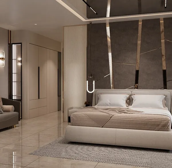 A luxurious master bedroom where comfort meets high-end design. The space includes a plush upholstered bed, a full seating area, and a striking feature wall with marble panels and metallic accents.