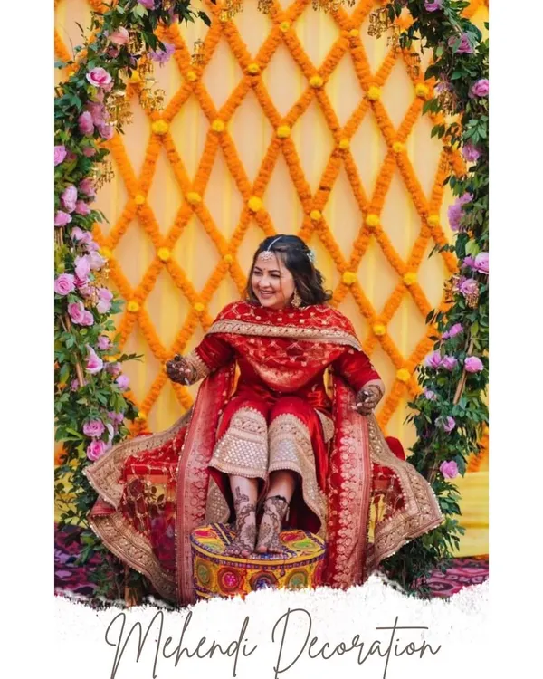 Here is a beautiful mehendi setup I did, with the bride seated for her ceremony. The backdrop is a lattice of orange marigolds against yellow drapes, framed by columns of fresh pink flowers and green leaves.
