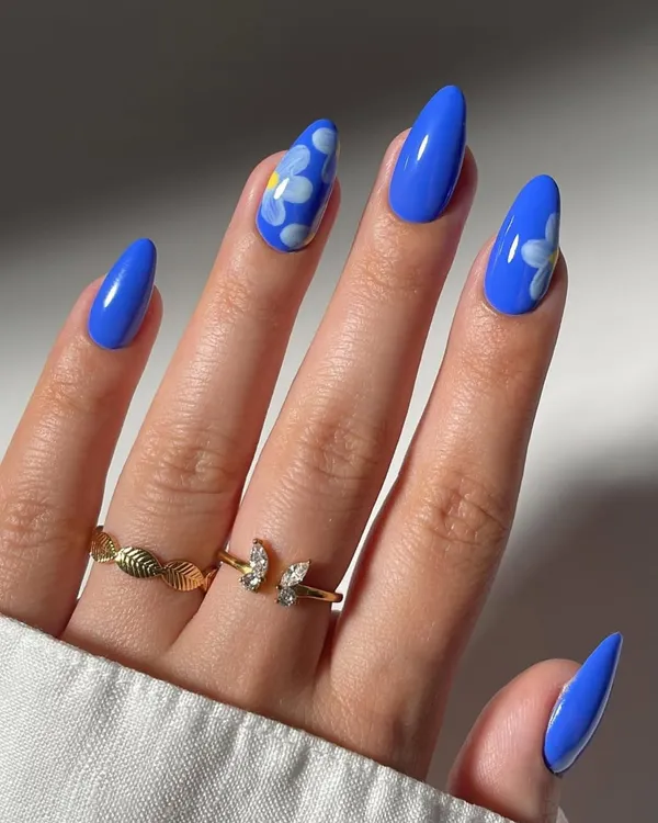 A vibrant and playful design featuring hand-painted daisies on a bold blue base. This look on almond-shaped nails shows our ability to create fun, floral nail art that pops with color.