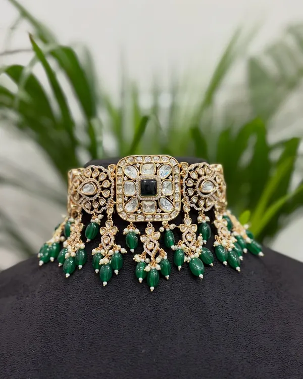 This is a classic Kundan choker with a central black stone and emerald green bead drops. It's a versatile rental piece that pairs well with many traditional outfits.