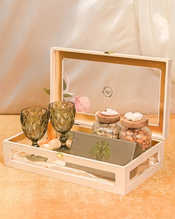 This sophisticated Rakhi hamper is perfect for a sibling with refined taste. It features two elegant wine glasses, jars of premium nuts, and a personalized card, all presented in a beautiful wooden keepsake box.