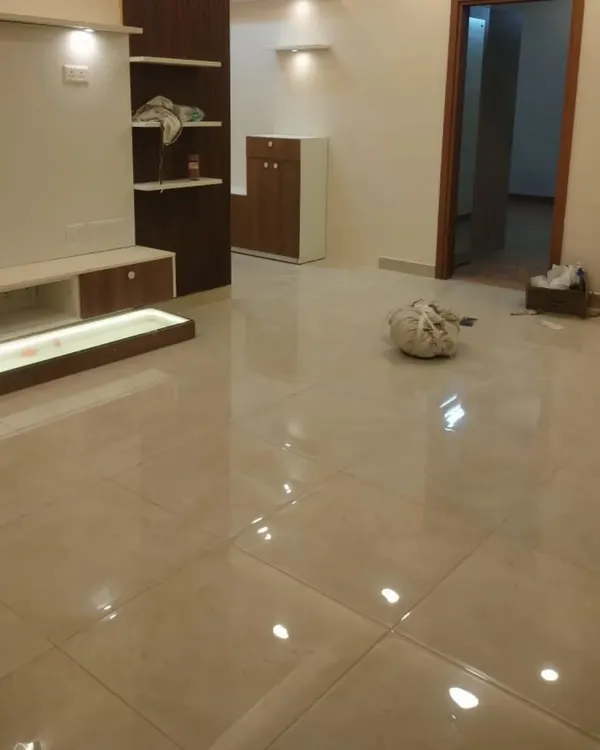 A spacious living room after a fresh coat of paint. The walls are finished in a warm, neutral off-white, creating a bright and airy feel. Notice the clean lines and glossy tiled floor, which we carefully protected during our work.