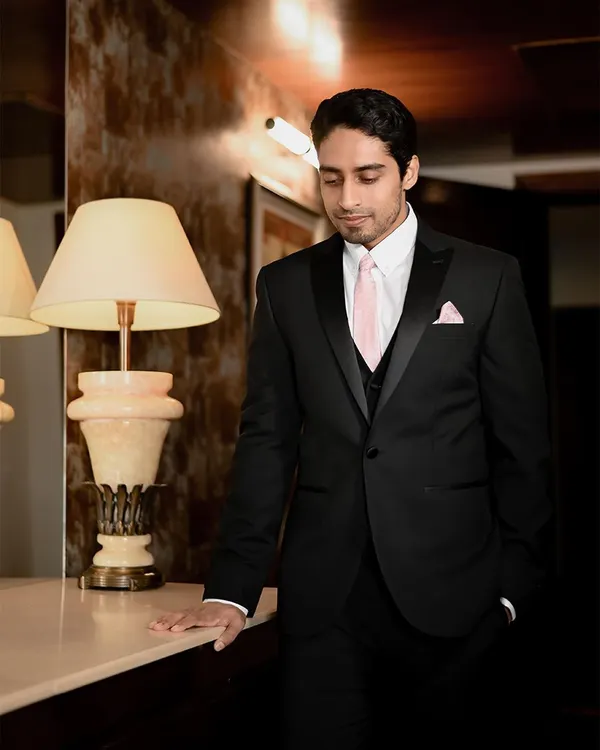 A classic portrait of the groom looking sharp in his black tuxedo at the Noor Mahal Palace. The warm, ambient lighting creates a sophisticated and timeless look.