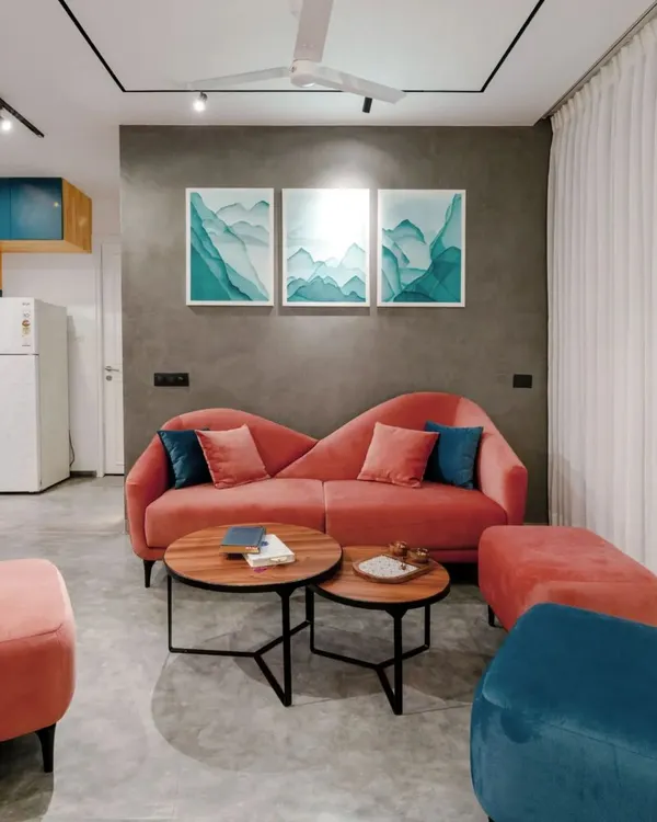 The living room of the T7 & T8 apartment features a custom blush-colored sofa that provides a beautiful pop of color against the grey textured wall and polished concrete floor.
