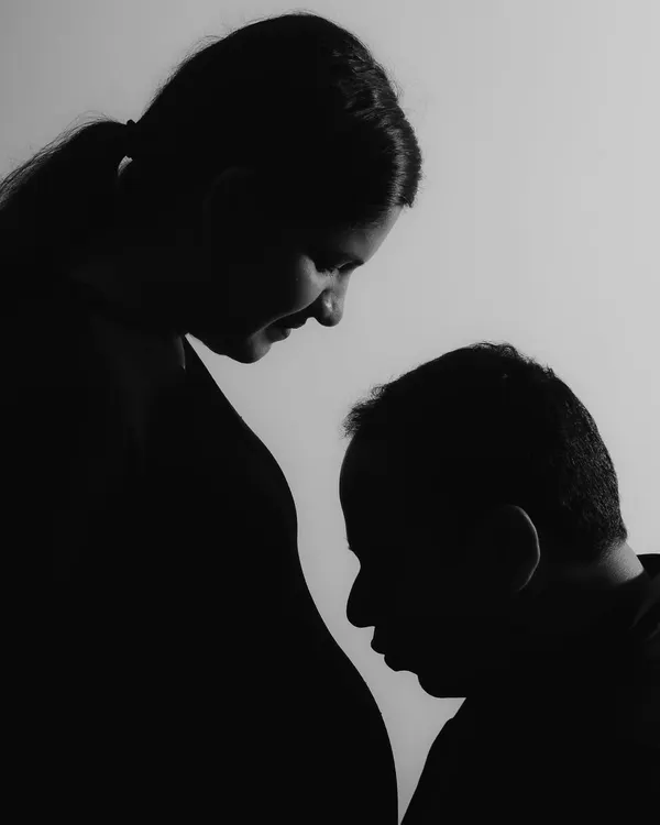 A signature artistic silhouette, this black and white image is all about emotion. The father-to-be's gentle gesture towards the baby bump creates a powerful and iconic maternity portrait.