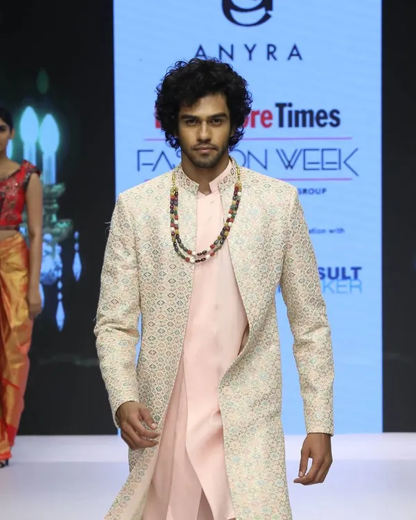 From my Bangalore Times Fashion Week collection, this Indo-Western look features a light pink kurta and pants layered with a long, embroidered overcoat. It's a stylish and contemporary option for any celebratory event.