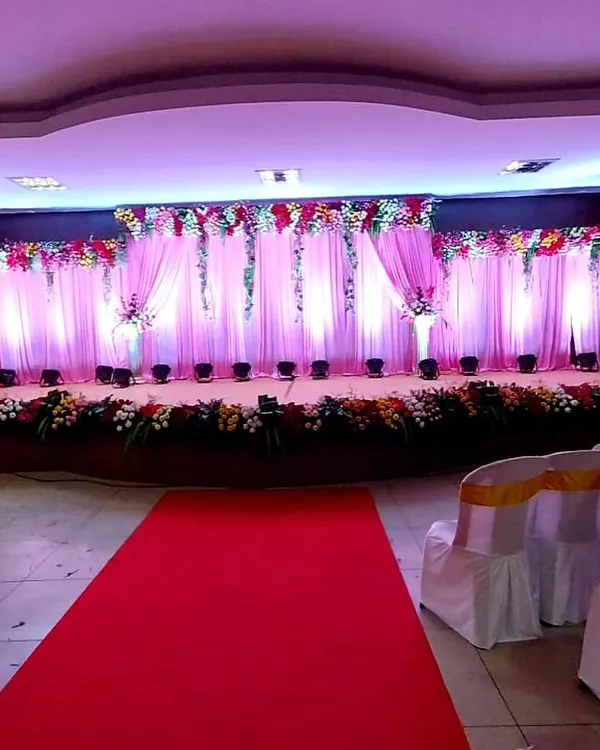 A classic stage decoration I created for a wedding reception. The design features a backdrop of soft pink drapery, accented with floral arrangements and illuminated by professional uplighting.