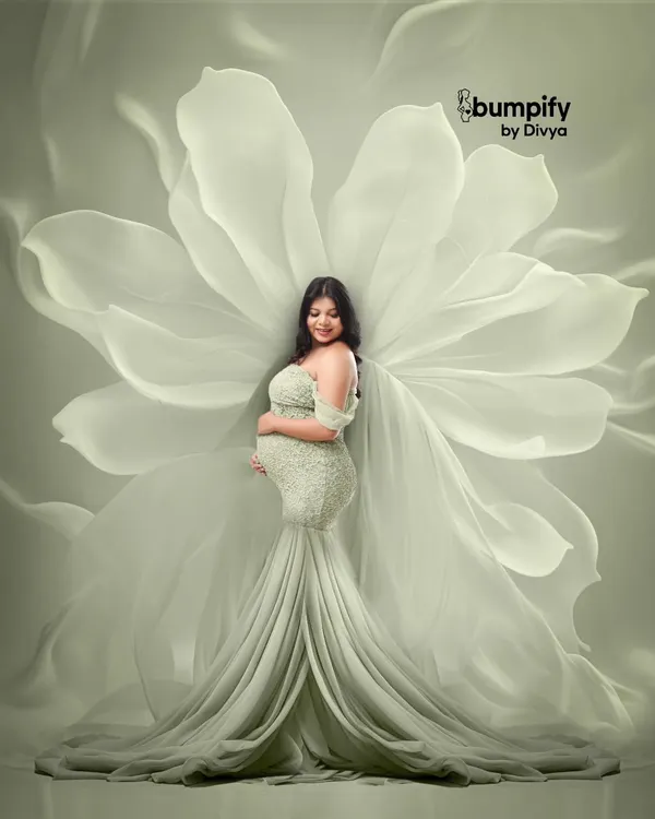 A truly angelic portrait of a mom-to-be in a light green gown, with a backdrop of giant, ethereal white flower petals that look like wings. This is one of my most popular fine art maternity setups.