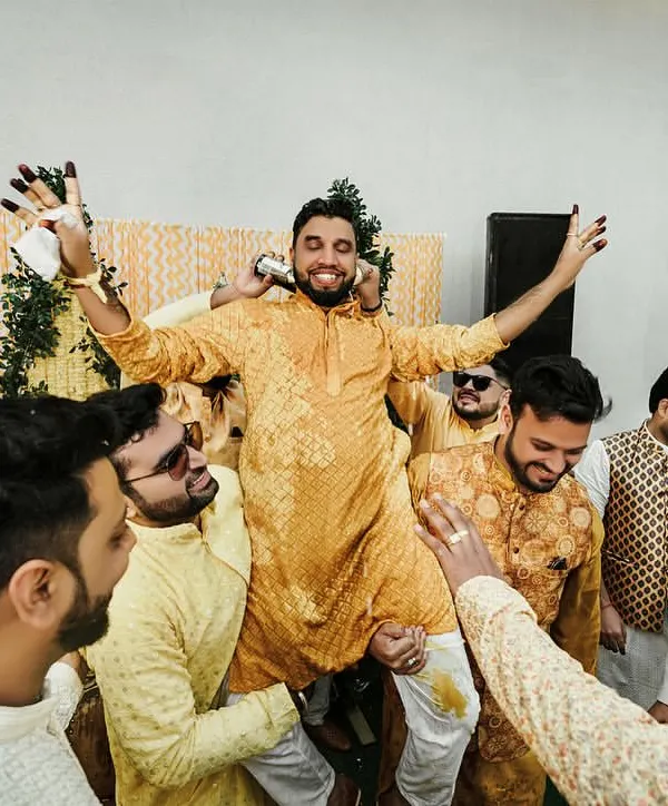 The groom is lifted up by his friends during the Haldi ceremony. These are the moments of friendship and celebration that make weddings so special.