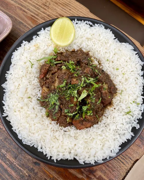 Our signature Pandi Curry, the heart of our Kodava heritage. We slow-cook chunky, juicy pork for hours with garlic, coriander, and peppery spices from our family estate, served here on a bed of hot white rice with a squeeze of lime.