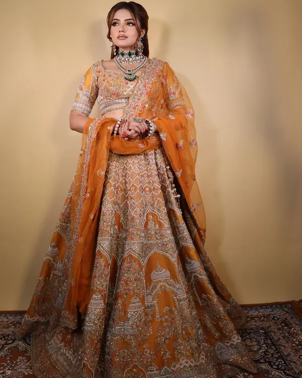 The "Marigold Muse" in her full glory. This image showcases the complete look with the stunning orange lehenga, a perfect inspiration for a vibrant wedding event.
