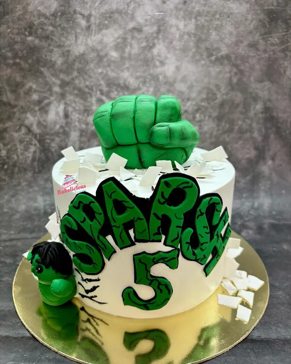 Hulk smash! This action-packed cake features a powerful fondant fist bursting through the top and a mini Hulk figure. The graffiti-style name makes it a cool centerpiece for a 5th birthday.