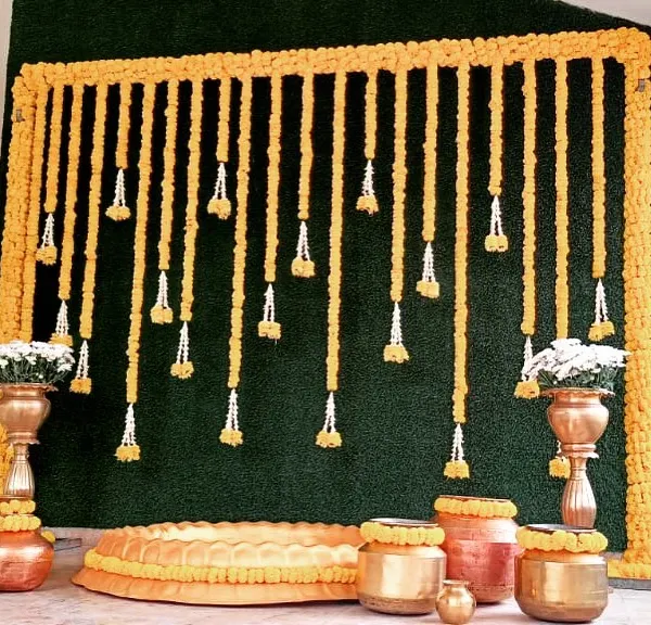 A classic Haldi ceremony setup we did, featuring a backdrop of marigold garlands and a collection of traditional brass and copper pots (urulis).