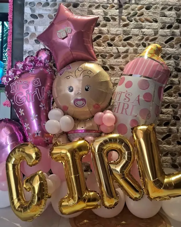 Celebrating a new arrival? We create stunning balloon arrangements like this 'It's a Girl' bouquet to make your baby shower unforgettable. This setup features large foil letters, a baby-shaped balloon, and a mix of pink and gold accents.