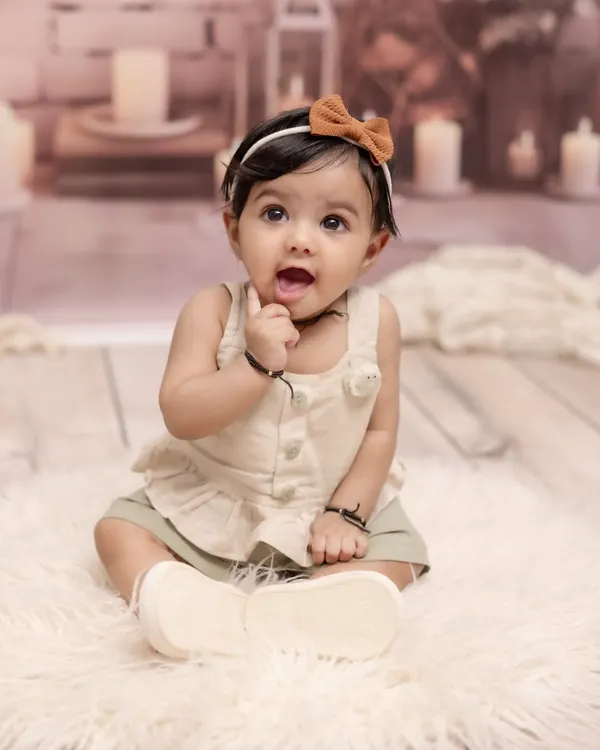 Capturing that curious and adorable sitter stage. This simple and sweet portrait of a baby girl, sitting up and exploring, focuses on her bright eyes and charming personality against a soft, neutral background.