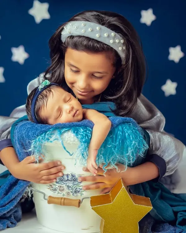 A proud big sister holds her new baby sibling. I guide older children to interact gently and lovingly, resulting in authentic portraits that showcase their special new bond.