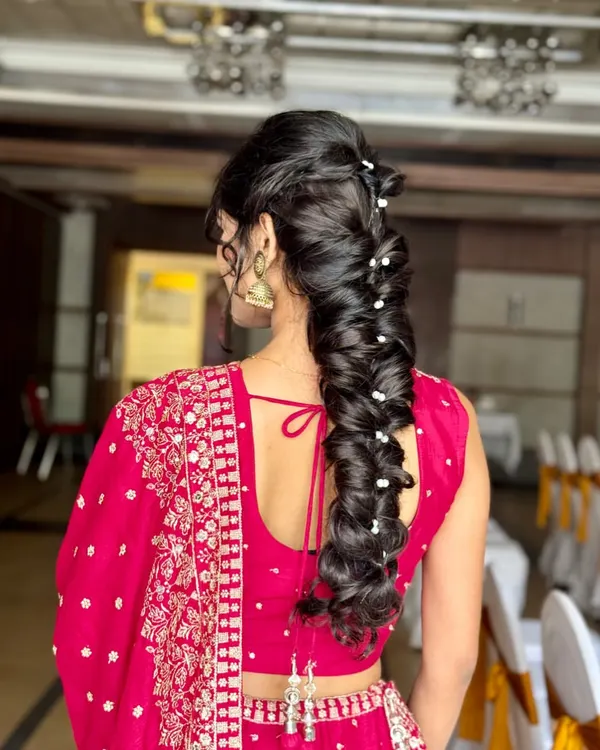 Letting the hair flow like ocean waves. This stunning and intricate mermaid braid, adorned with small pearls, is a perfect statement hairstyle for a lehenga or gown.