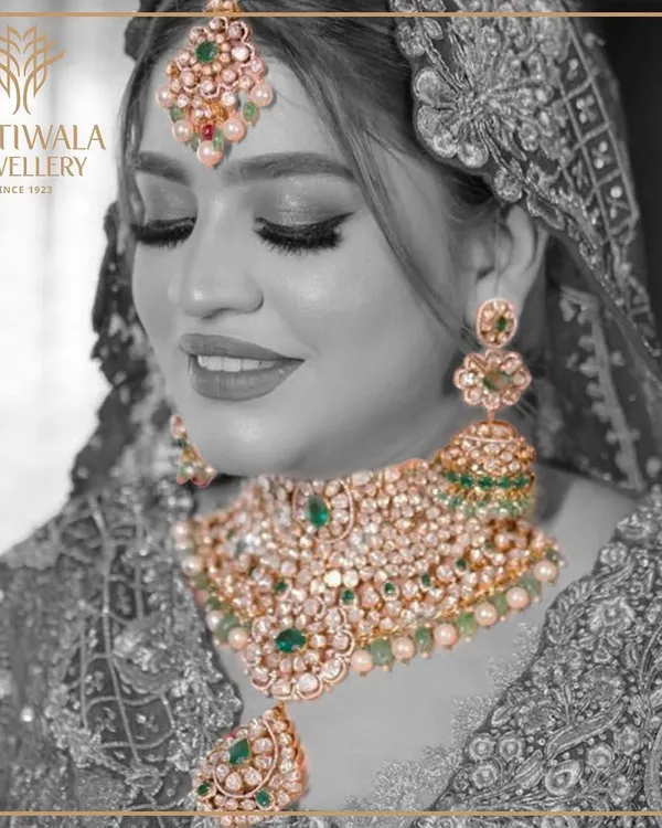 A vision of bridal splendor. This complete bridal set, featuring a magnificent choker, matching earrings, and maang tikka, is crafted with uncut Polki diamonds and vibrant emeralds, embodying the grandeur of traditional Indian weddings.